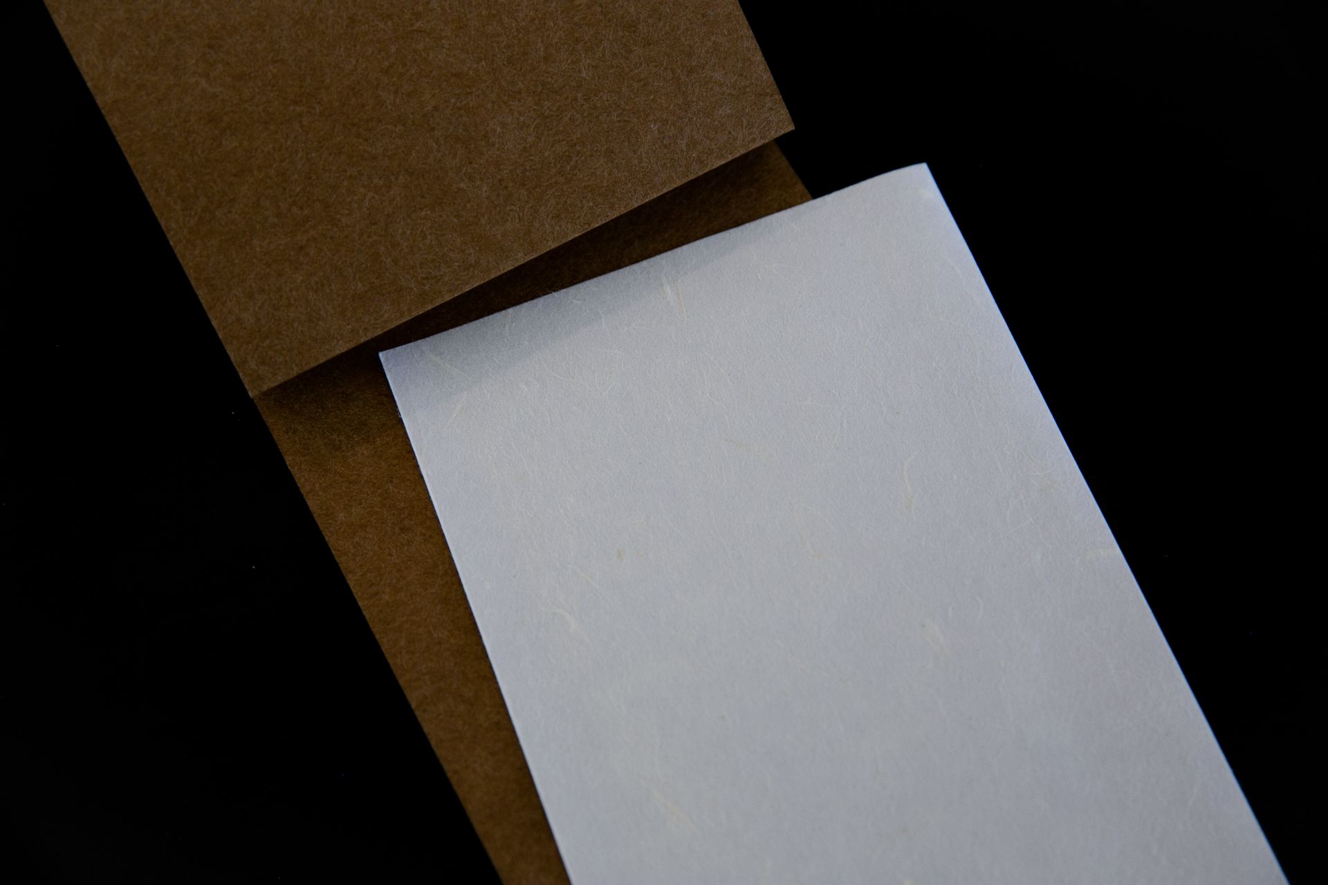 Abstract minimalist design with brown and white paper on a black background, perfect for backgrounds.