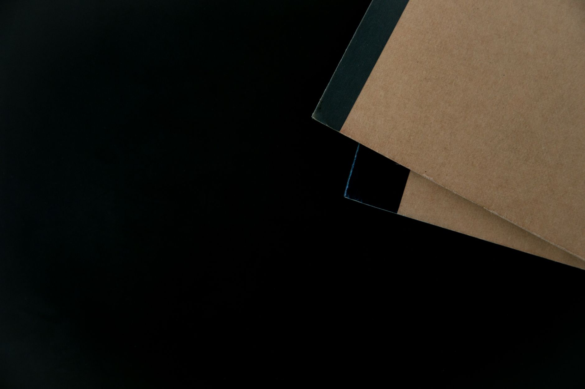 Brown notebooks with black binding on a dark surface, ideal for stationery themes.
