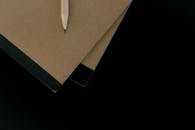 A Pencil on Top of Brown Notebooks