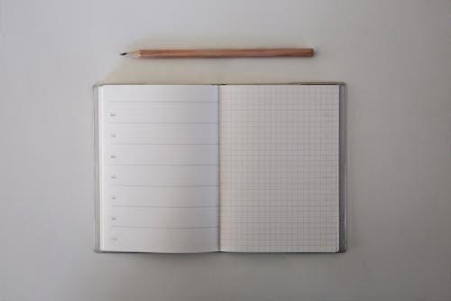 A White Graphing Paper Beside a Brown Pencil