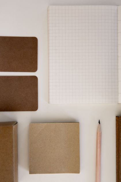 Kraft notebooks, grid paper and a pencil laid out on white — photo by PNW Production on Pexels