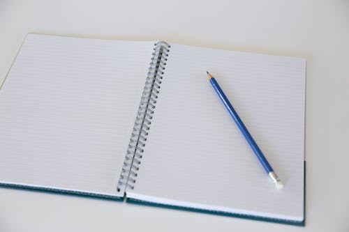 Free Photo of a Blue Pencil on a Blank Page of a Notebook Stock Photo