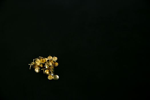 A neat arrangement of gold thumbtacks against a dark background, ideal for minimalistic designs.