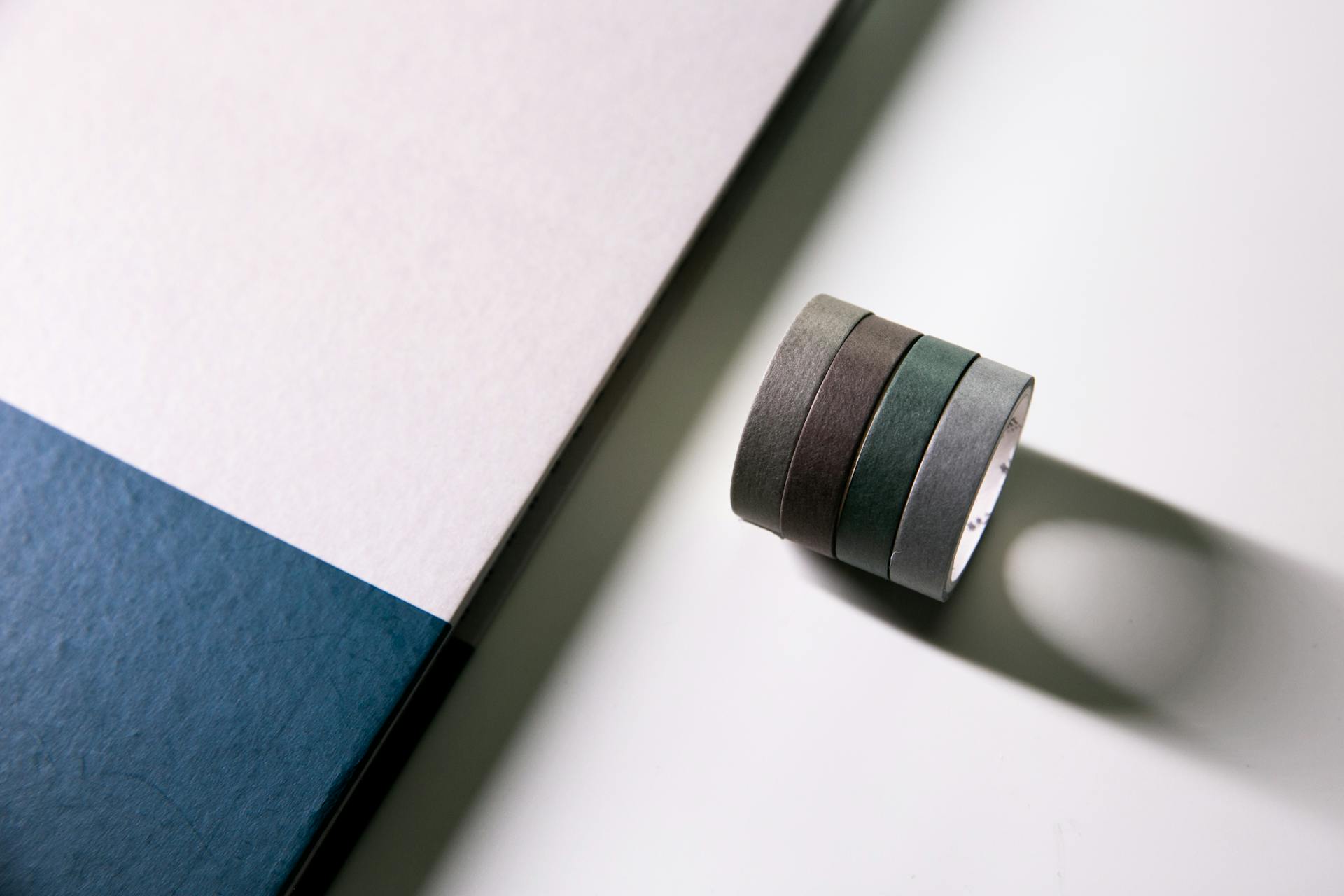Stack of colored adhesive tape with geometric paper shapes, ideal for minimalist office themes.