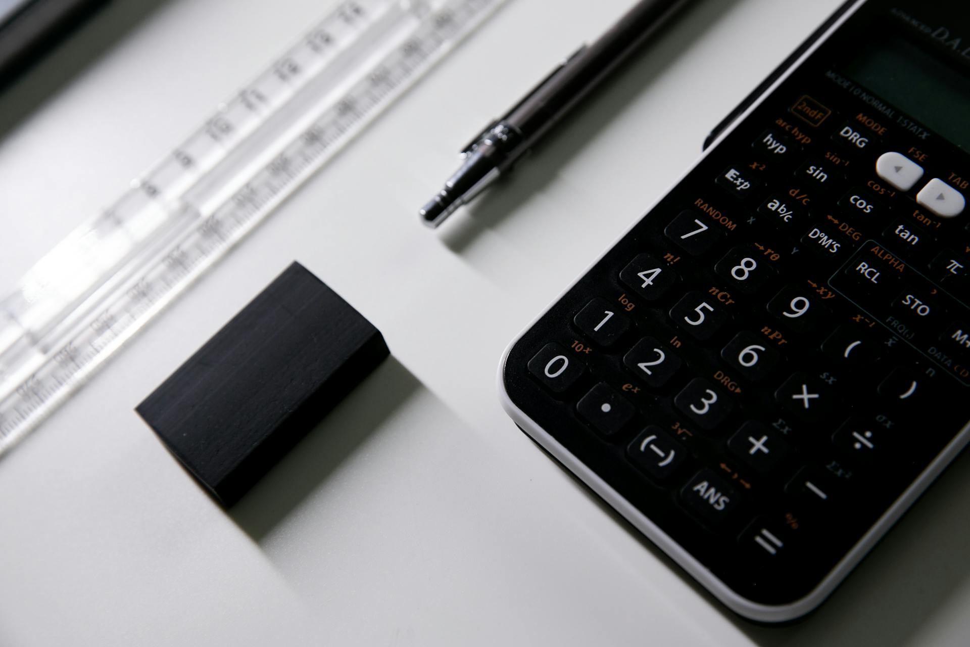 Close-up of a scientific calculator, ruler, and eraser on a desk, ideal for math or exam study visuals.