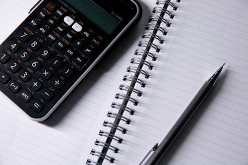 Free Close-up of an Open Notebook, Calculator and a Pen  Stock Photo