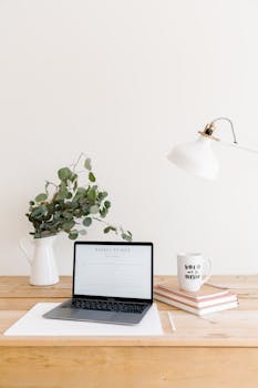 Clean and organized workspace featuring a laptop, lamp, and eucalyptus plant.