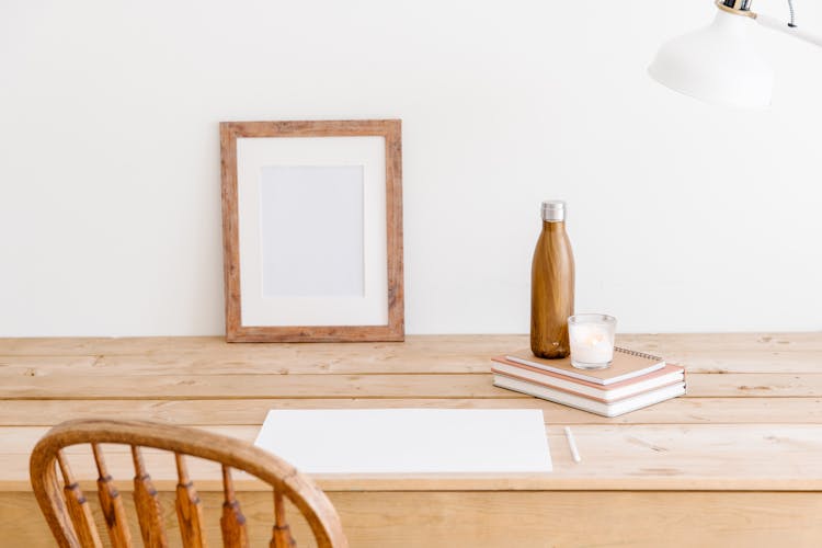 Bottle, Notebooks, Frame And Paper Sheet On Table