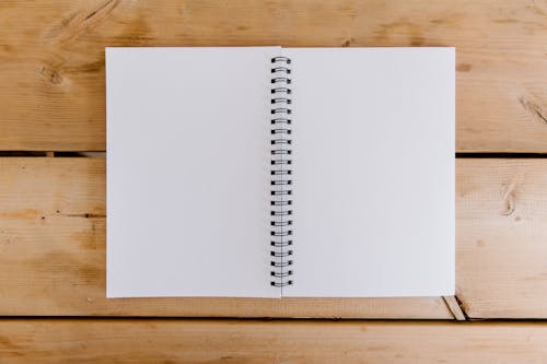 Open Spiral Binded Notebook on a Wooden Desk