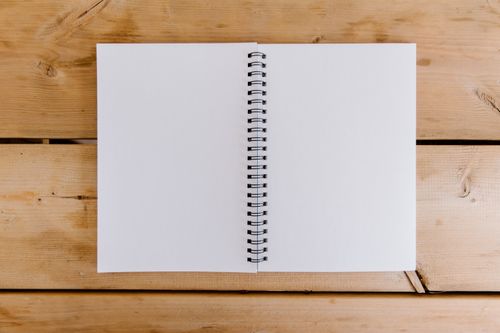 Free Top view of an open spiral notebook on a wooden desk, perfect for copyspace. Stock Photo