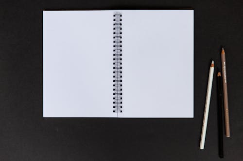 Darmowe zdjęcie z galerii z czarne tło, kolorowe ołówki, notatnik