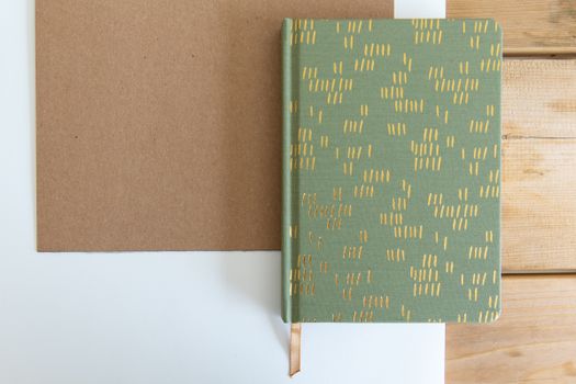 Notebook Lying on Piece of Cardboard on Wooden Desk