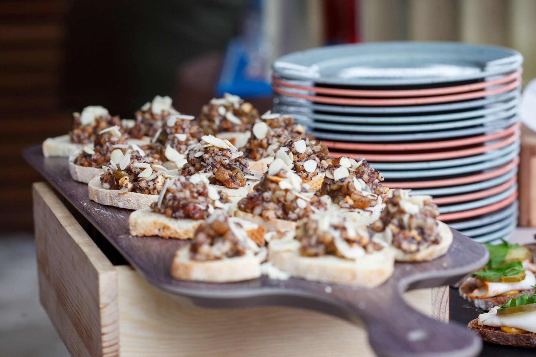 Sliced bread topped with nuts and dried fruits on a wooden platter, perfect for parties.