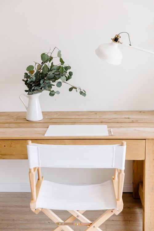 Free Minimalist wooden desk with eucalyptus and white decor for a calming workspace. Stock Photo