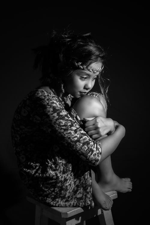 Grayscale Photo of a Girl Sitting on a Chair