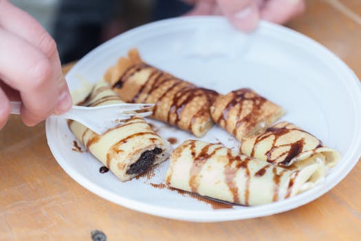 Close-up of pancake rolls drizzled with chocolate on a plate, showcasing a delicious dessert scene.