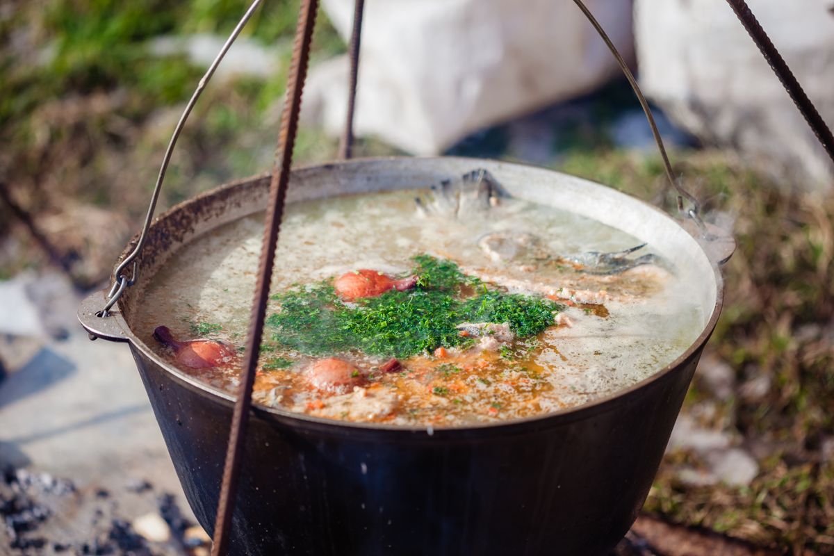 Large pot of broth simmering slowly with herbs, illustrating the long low-temperature cooking used to extract gelatin from bones