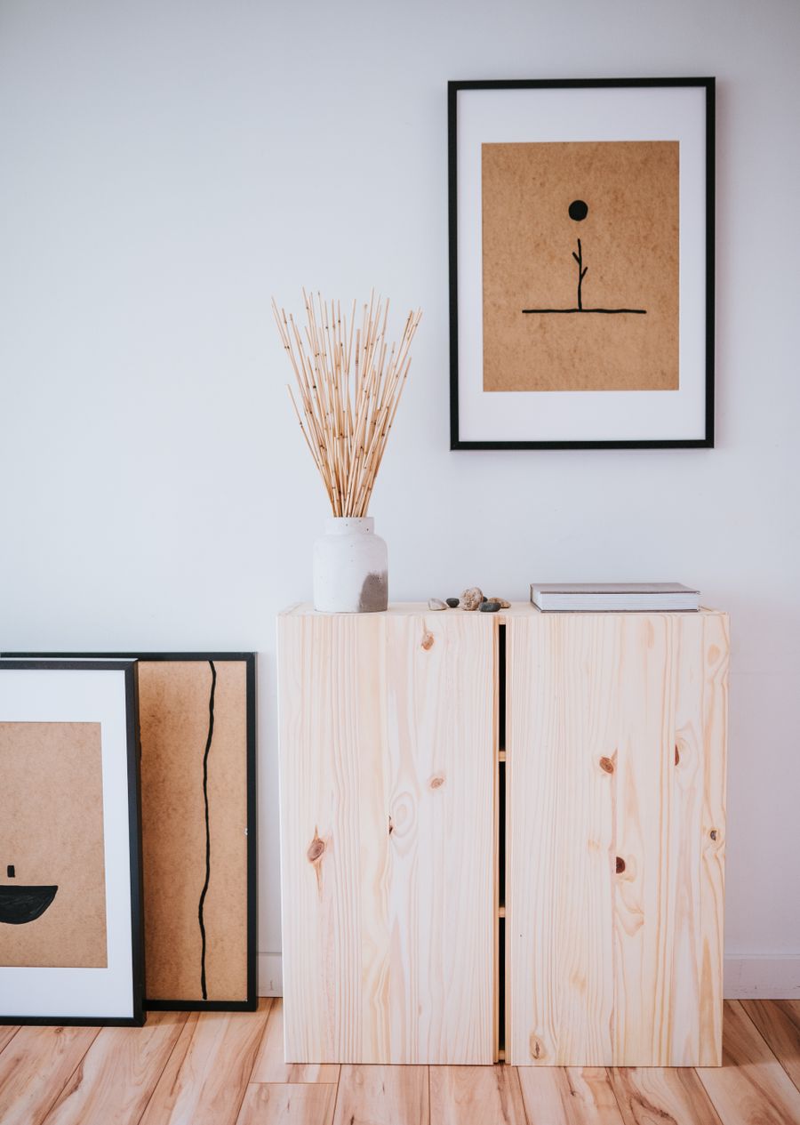 Timber cabinet with a rattan vase and framed line drawing above