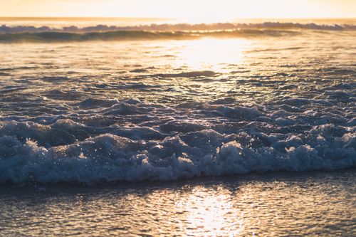 Free Golden hour sunlight reflecting on ocean waves at Arraial do Cabo beach, Brazil. Stock Photo