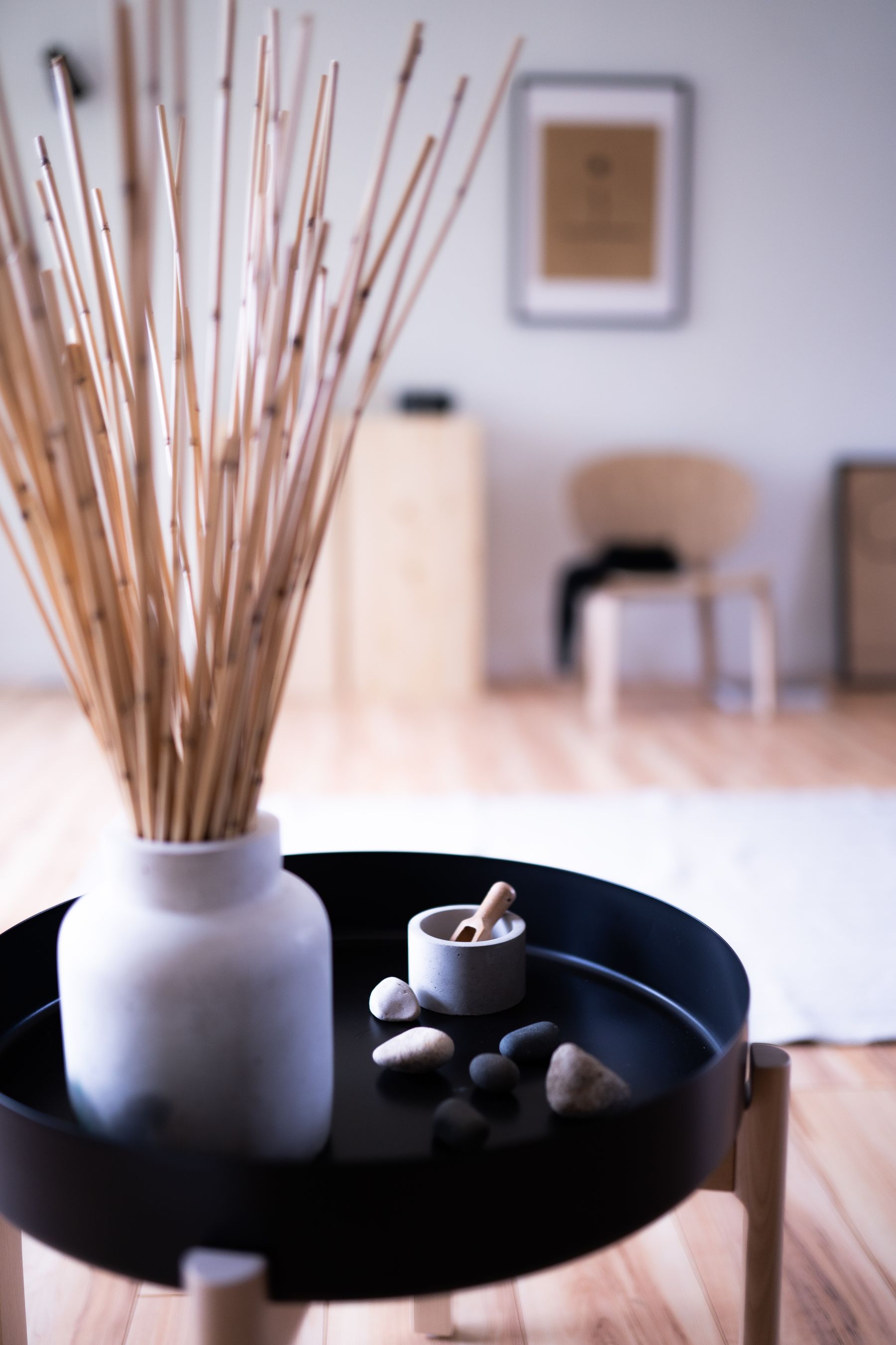 Round low wooden table styled with a small ceramic vessel in a restrained interior