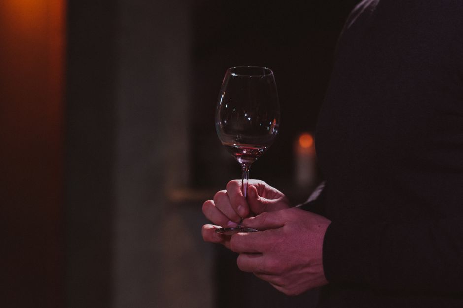 A glass of wine held against a white background to check color and clarity