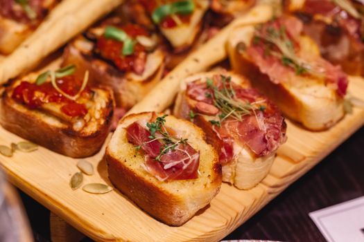 Delicious bruschetta with prosciutto and herbs served on a rustic wooden board. Perfect for appetizers.