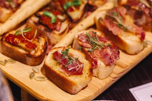 Free Delicious bruschetta with prosciutto and herbs served on a rustic wooden board. Perfect for appetizers. Stock Photo