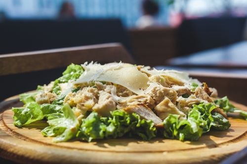 Free Delicious chicken Caesar salad with fresh lettuce and cheese on a wooden board. Stock Photo