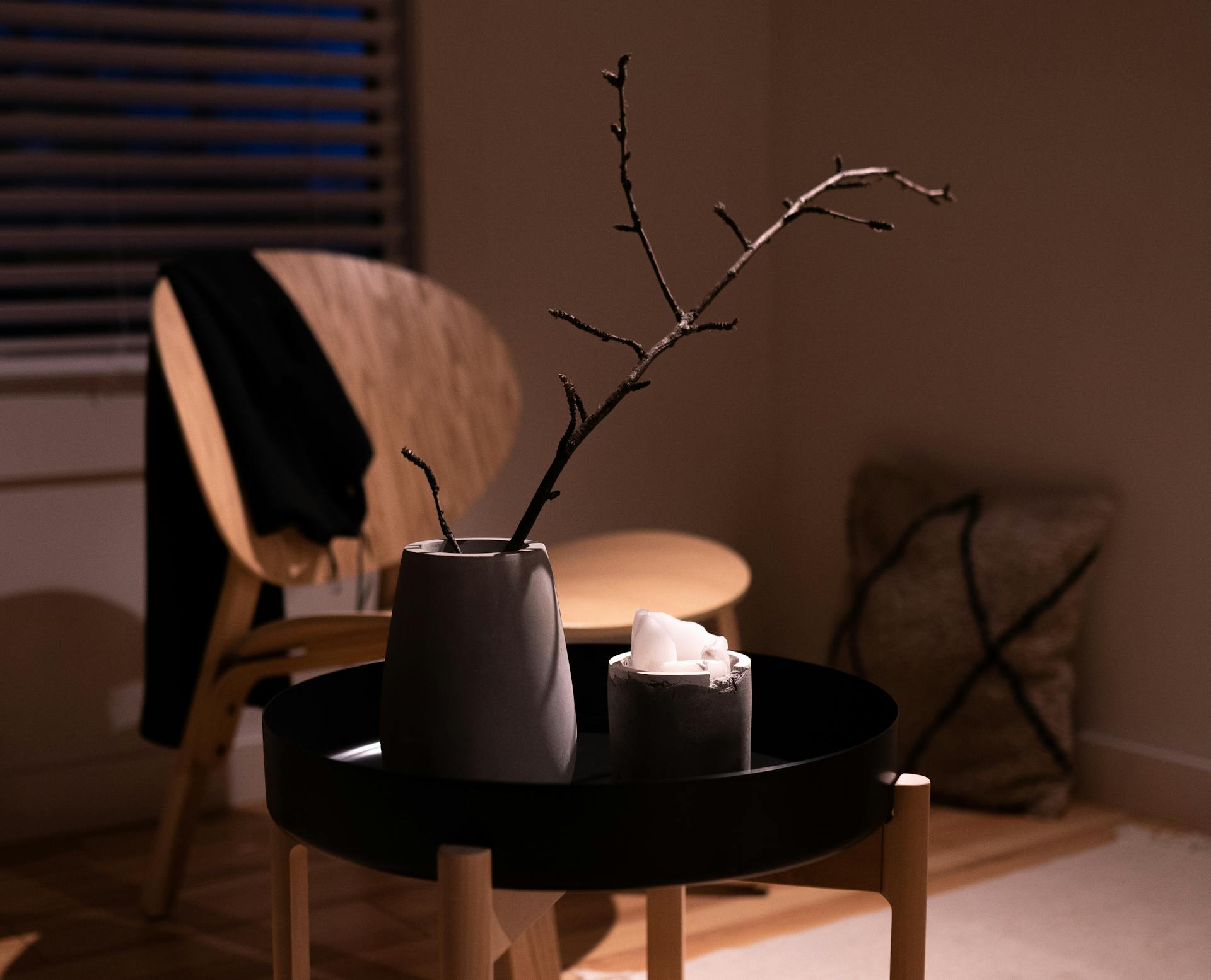 A cozy, minimalist interior featuring a vase with a branch on a table, creating a warm ambiance.