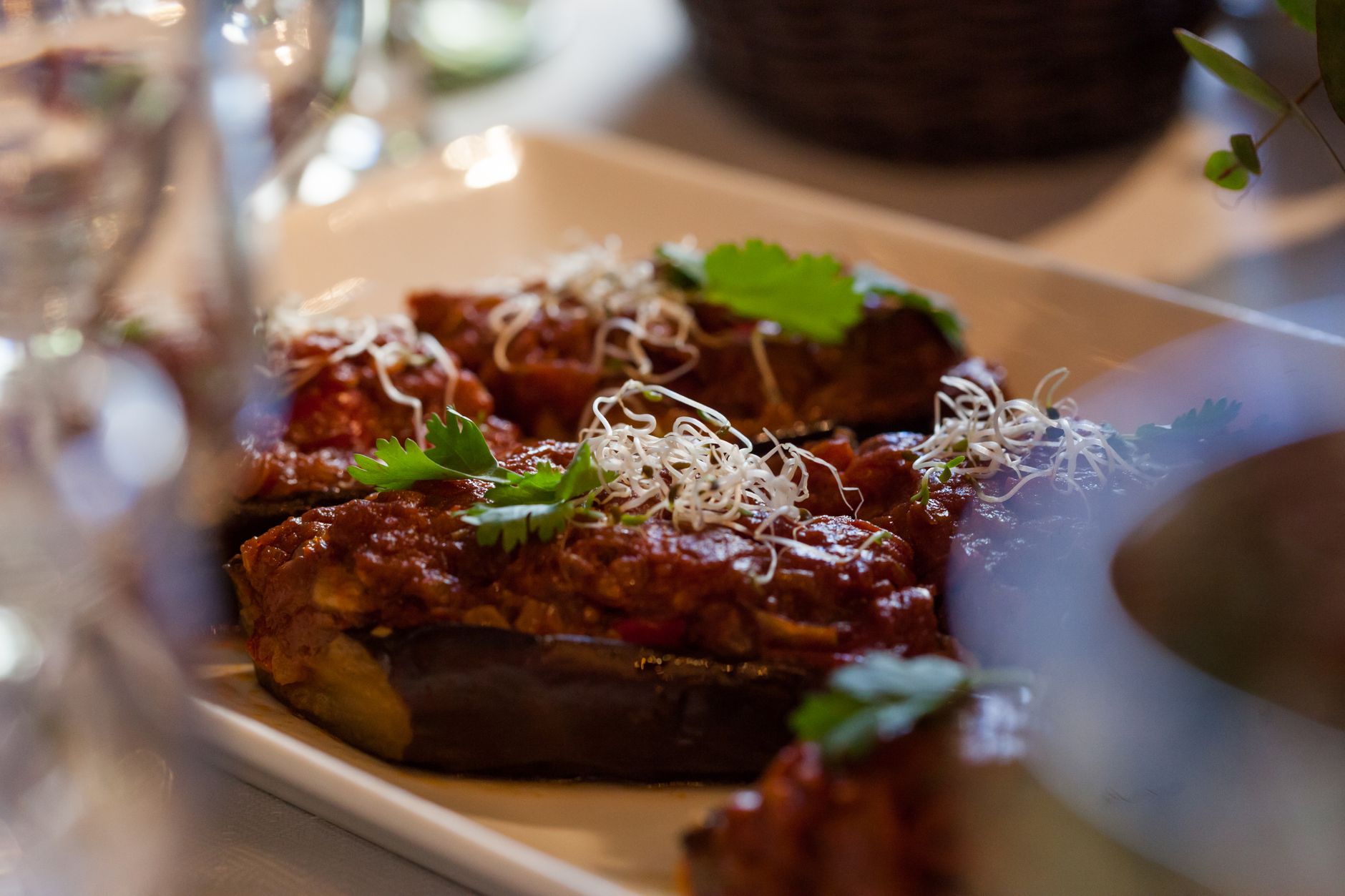 Close-up of stuffed eggplant topped with tomato sauce and garnished with herbs.