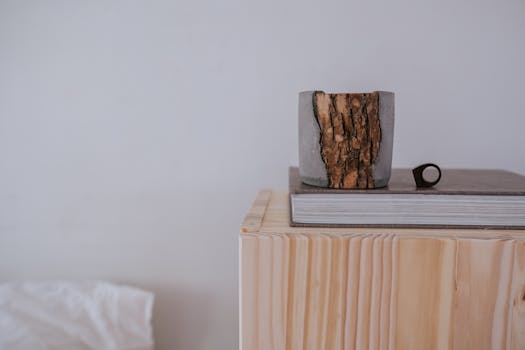 Aesthetic japandi decor featuring a wooden pot and book stack on a wooden cube against a neutral background.