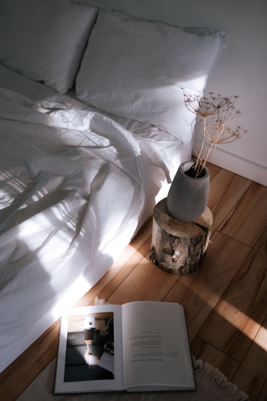 Quiet corner with sunlight across a timber floor, a vase and an open book