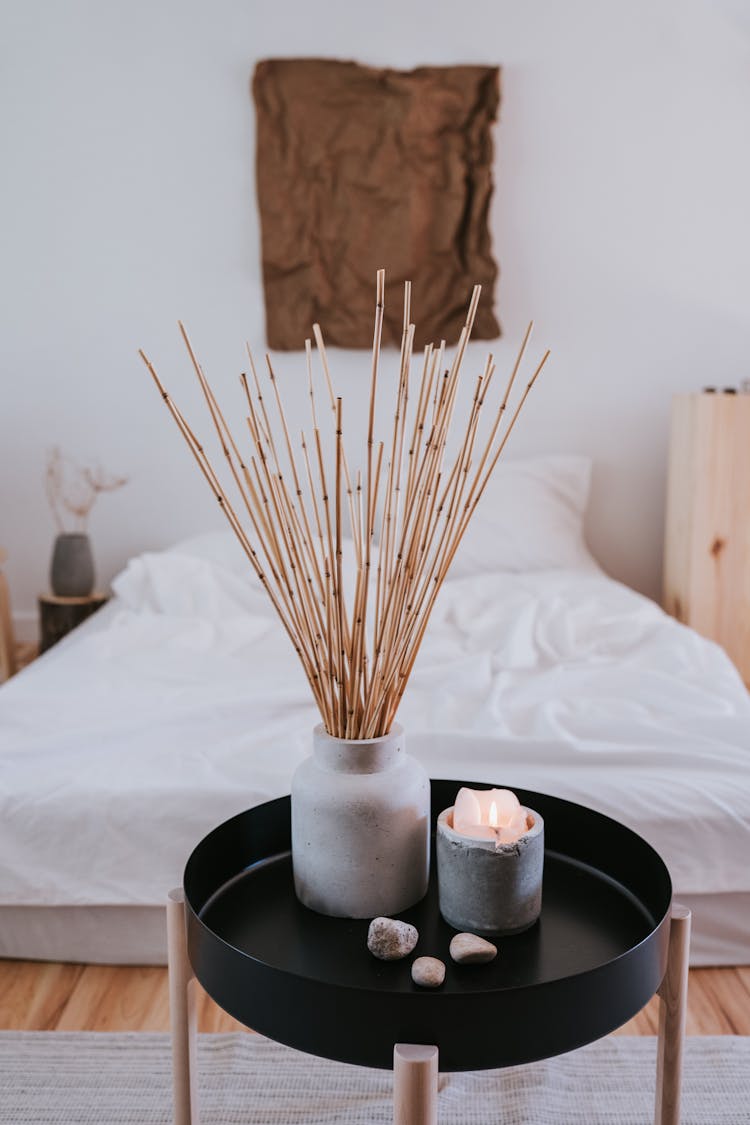 Sticks In Vase And Wax Cadle On Table