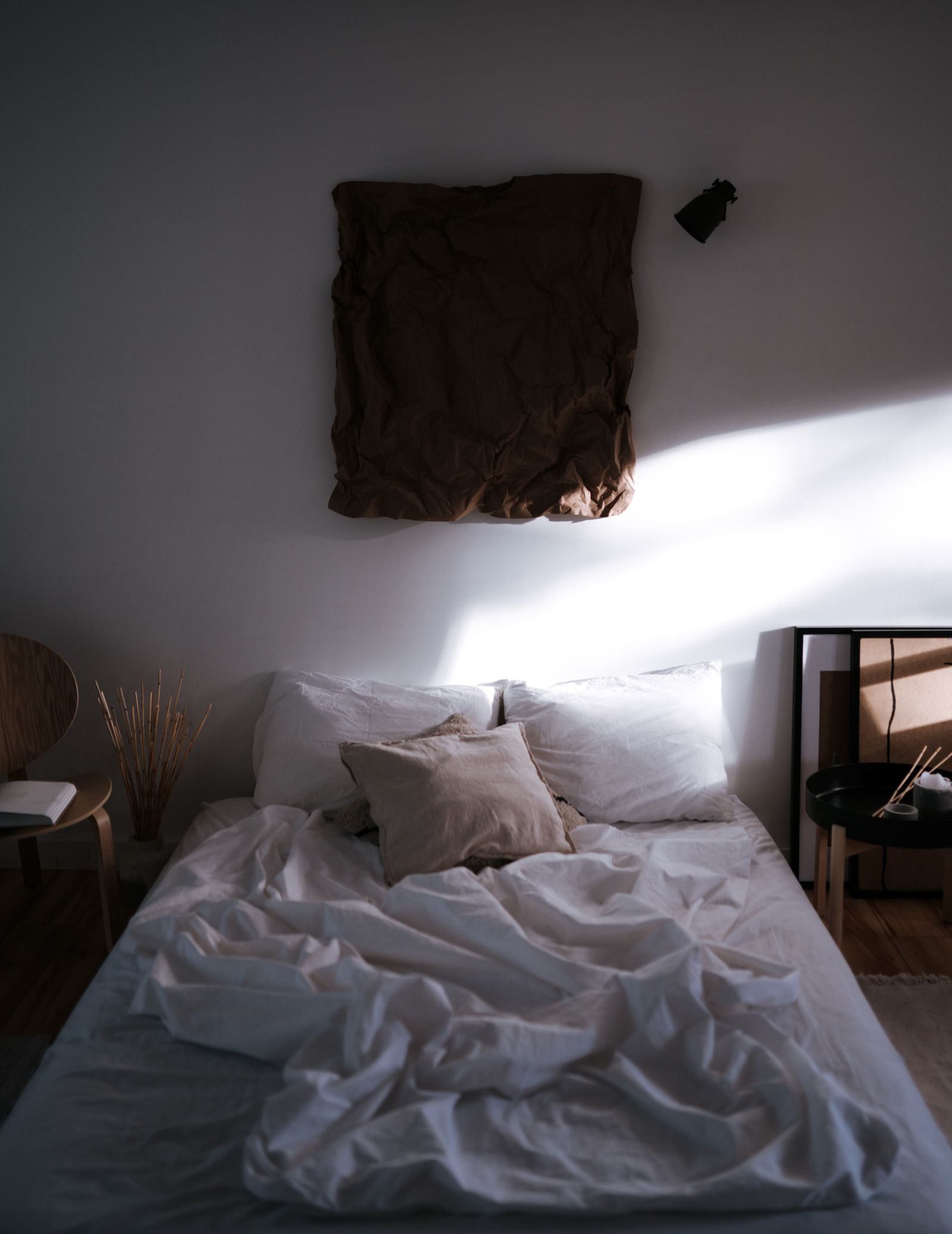 Cama com roupa de cama branca iluminada pela luz natural.