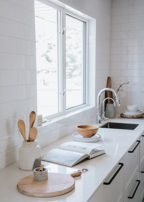 Free Serene japandi style kitchen featuring wooden utensils, faucet, and bright window. Stock Photo