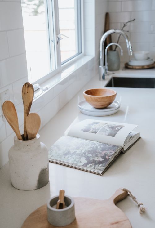 Free A serene Japandi style kitchen featuring natural light, wooden utensils, and an open book on the counter. Stock Photo