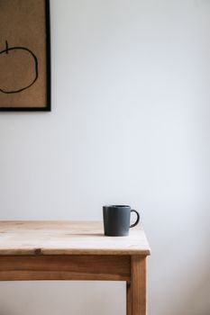 A minimalist ceramic mug on a wooden table with modern decor, perfect for cozy settings.
