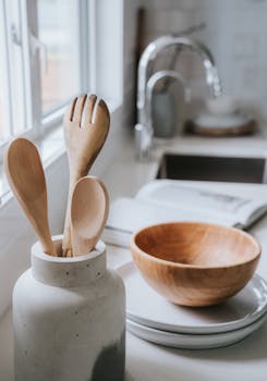 A serene minimalist kitchen scene showcasing wooden utensils and a bowl on a bright countertop.