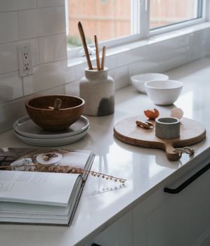 A modern kitchen counter showcasing natural decor elements like wooden bowls and ceramic plates by the window.
