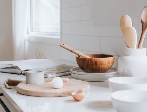 Free A serene minimalist kitchen setup featuring wooden bowls, spoons, and ceramic ware on a marble surface. Stock Photo