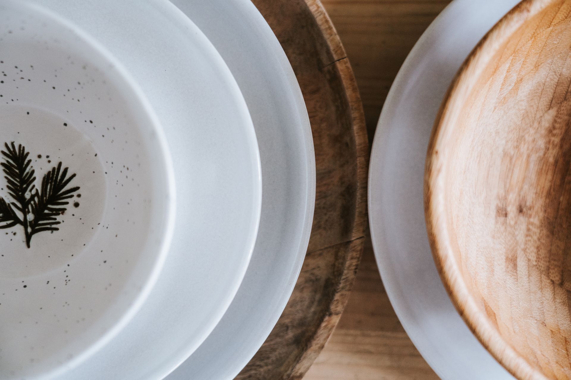 Top view of stacked ceramic and wooden plates showcasing minimalist and natural design elements.