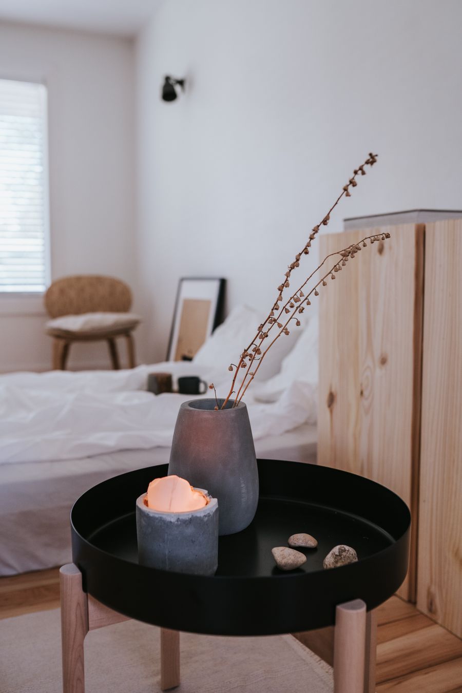 Minimal bedroom with a low wooden cabinet, round side table and soft daylight