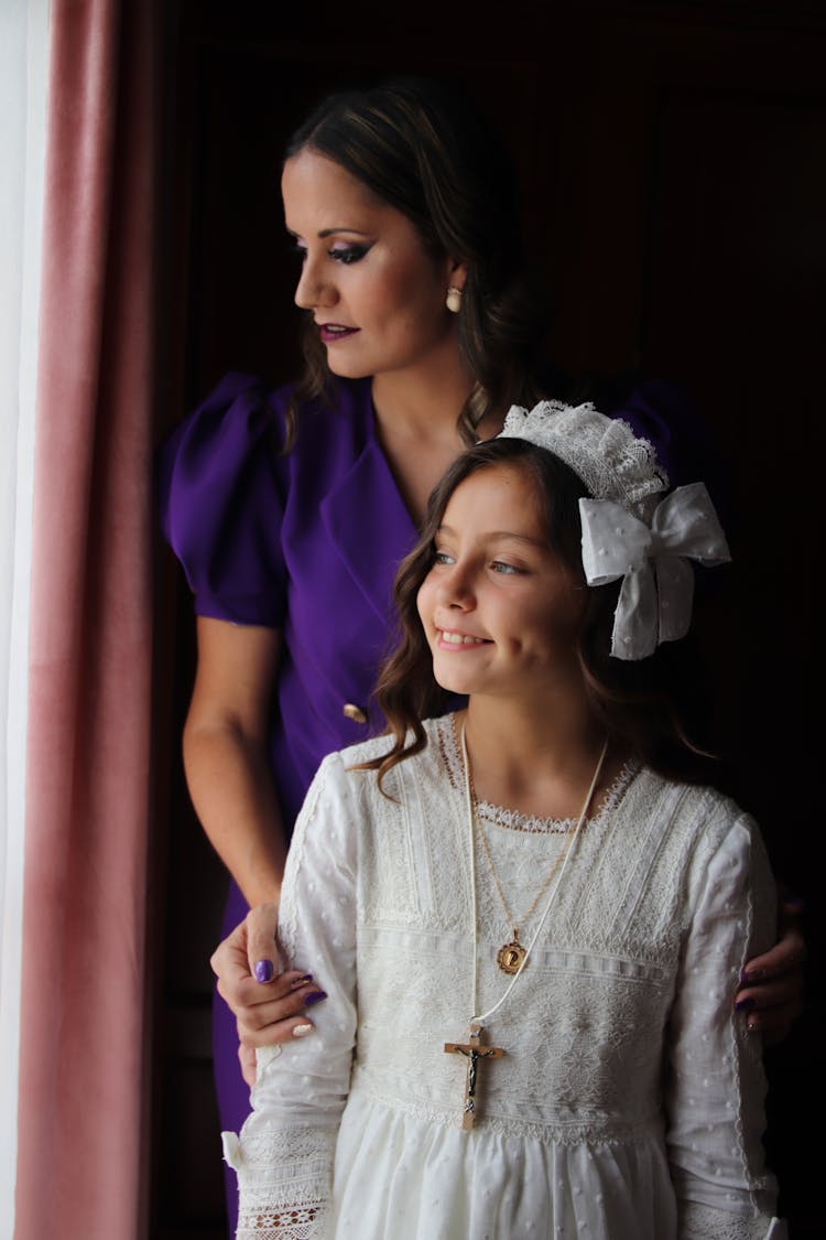 Portrait Of Woman In Purple Dress With Daughter In A White First Communion Dress With Cross