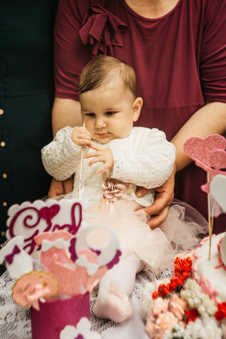 Adorable Baby Sitting Holding A Wooden Stick 