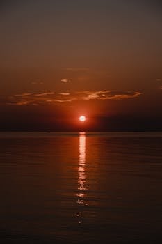 Beautiful sunset reflecting over the ocean with dramatic clouds and serene waters.