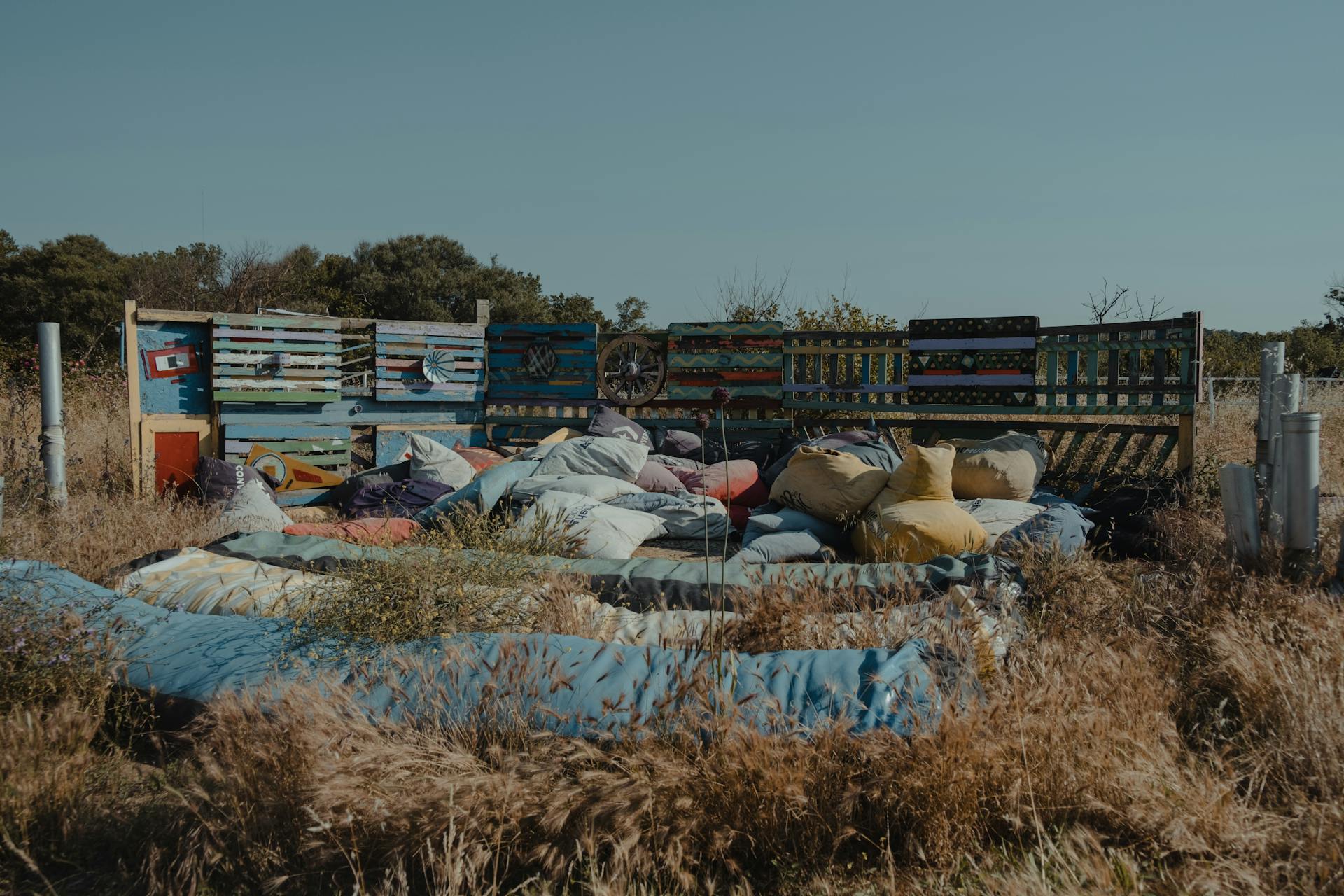 Artistic outdoor installation with colorful pallets and cushions in a rural setting.