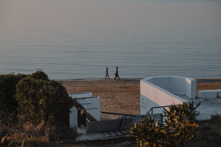 Men Walking On A Beach And White Architecture In Foreground