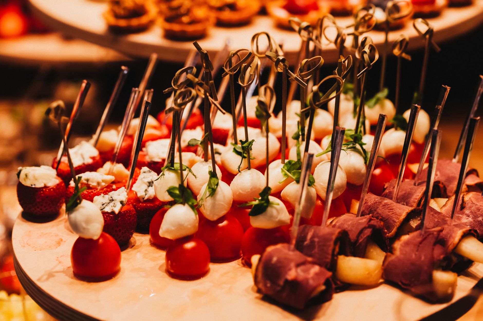 A vibrant display of skewered appetizers featuring cheese, tomatoes, and meats, ideal for gourmet catering.