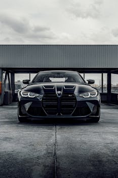 A sleek black luxury car parked in an industrial urban setting, showcasing modern design and elegance.