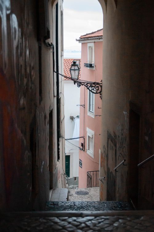 Free Narrow alleyway view with pastel buildings in Lisbon, Portugal's historic district. Stock Photo